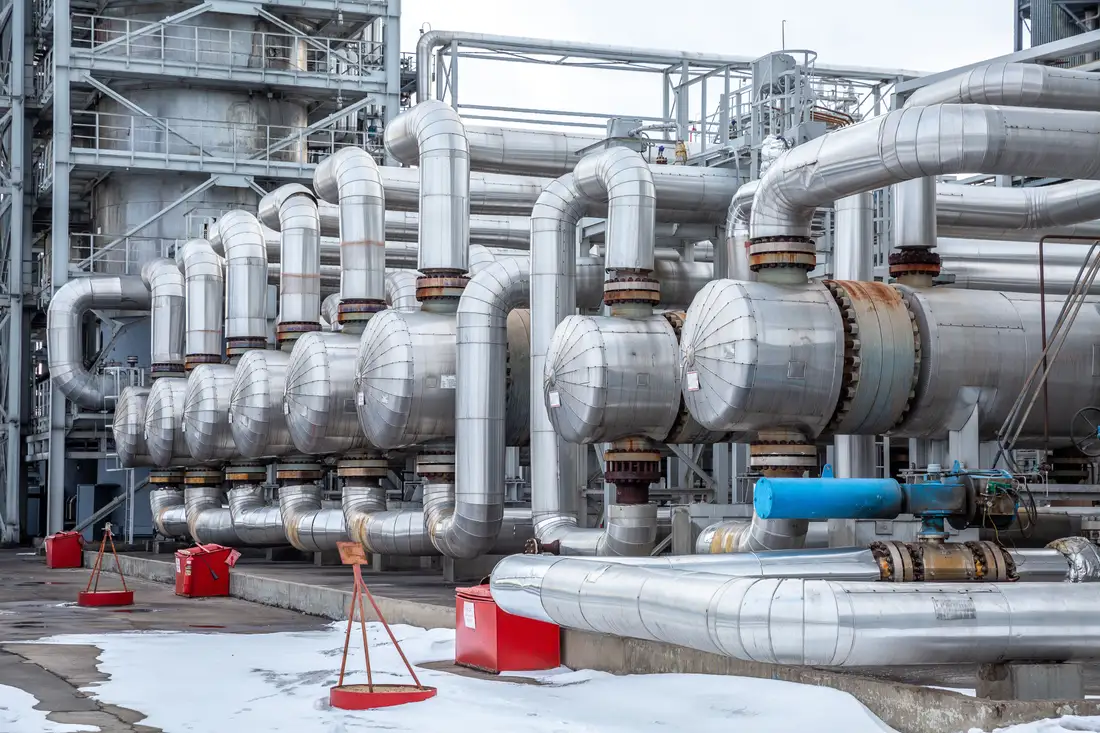 A row of insulated shell-and-tube heat exchangers and process piping at a plant in winter